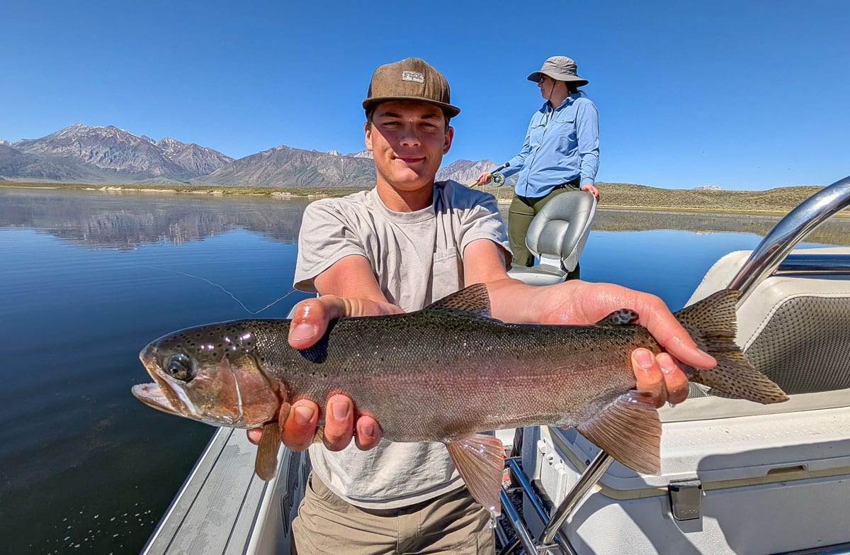 A fly fisherwoman holding a large rainbow trout on Crowley Lake near Mammoth Lakes, CA
