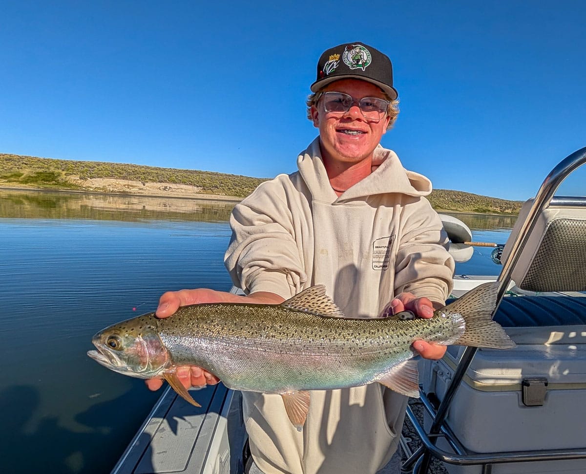 A fly fisherman holding a large brown trout on Crowley Lake near Mammoth Lakes, CA