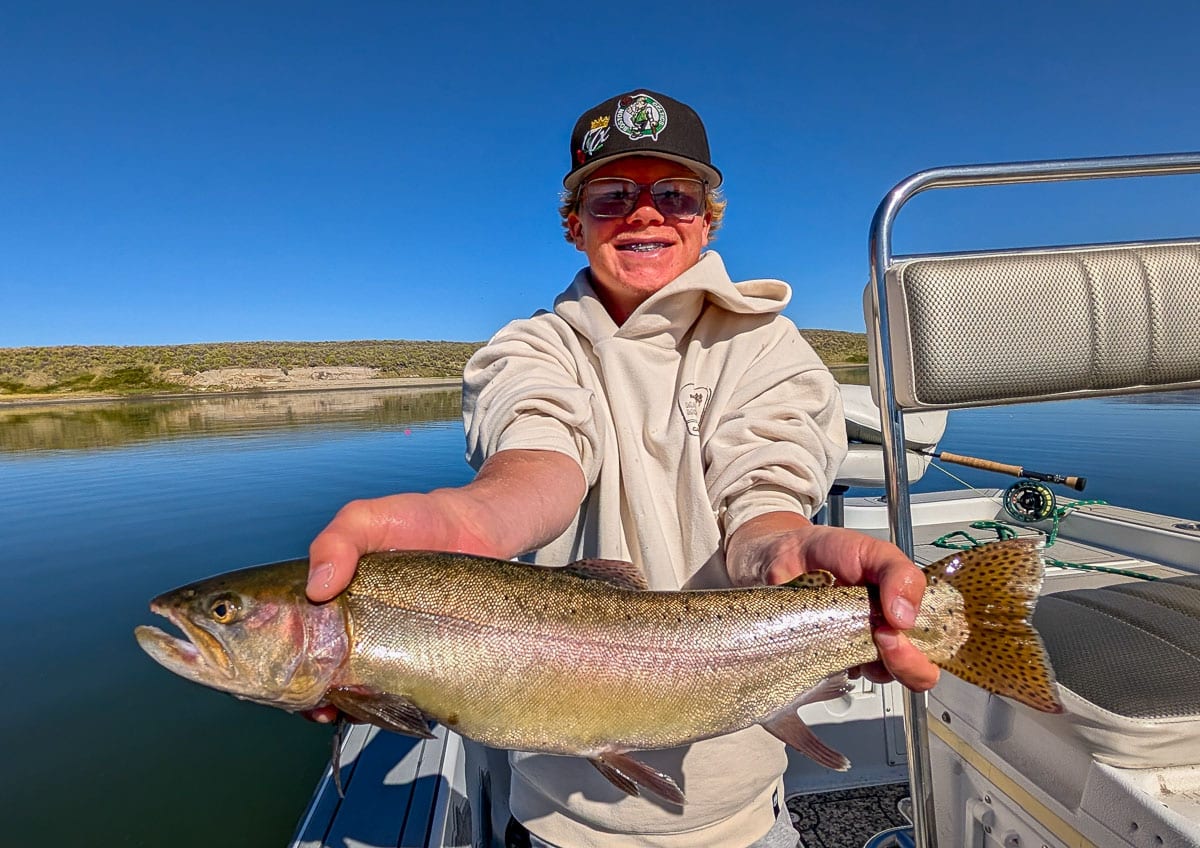 A fly fisherman holding a large rainbow trout on Crowley Lake near Mammoth Lakes, CA