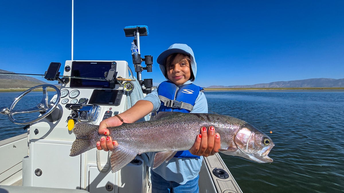 A fly fisherman holding a large cutthroat trout on Crowley Lake near Mammoth Lakes, CA