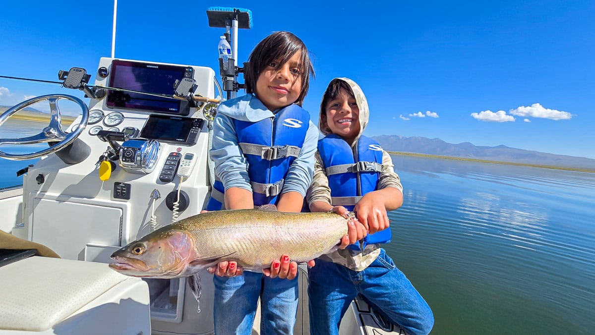 A female fly fisherman holding a large brown trout on Crowley Lake near Mammoth Lakes, CA