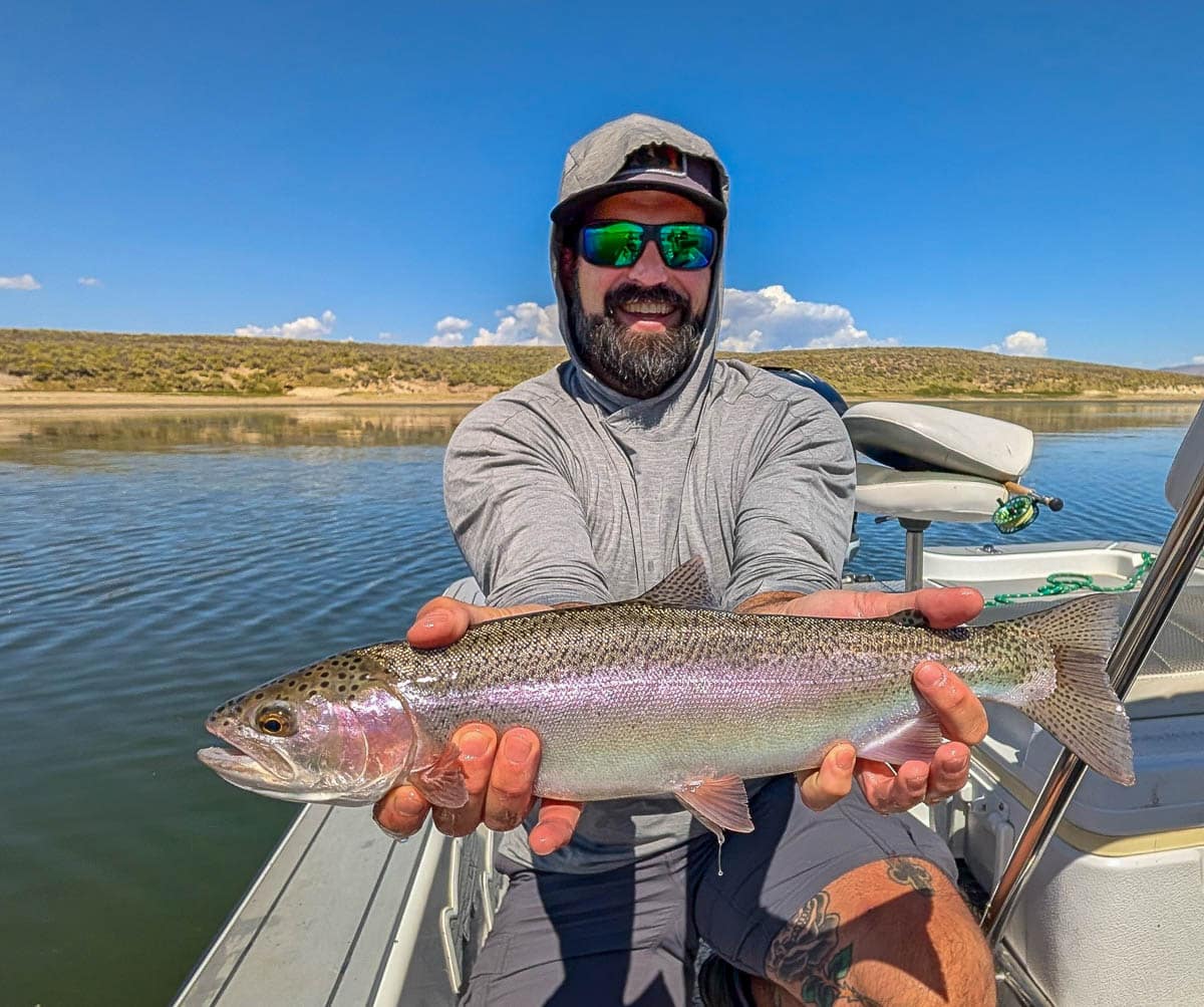 A fly fisherman holding a large rainbow trout on East Walker River near Bridgeport, CA