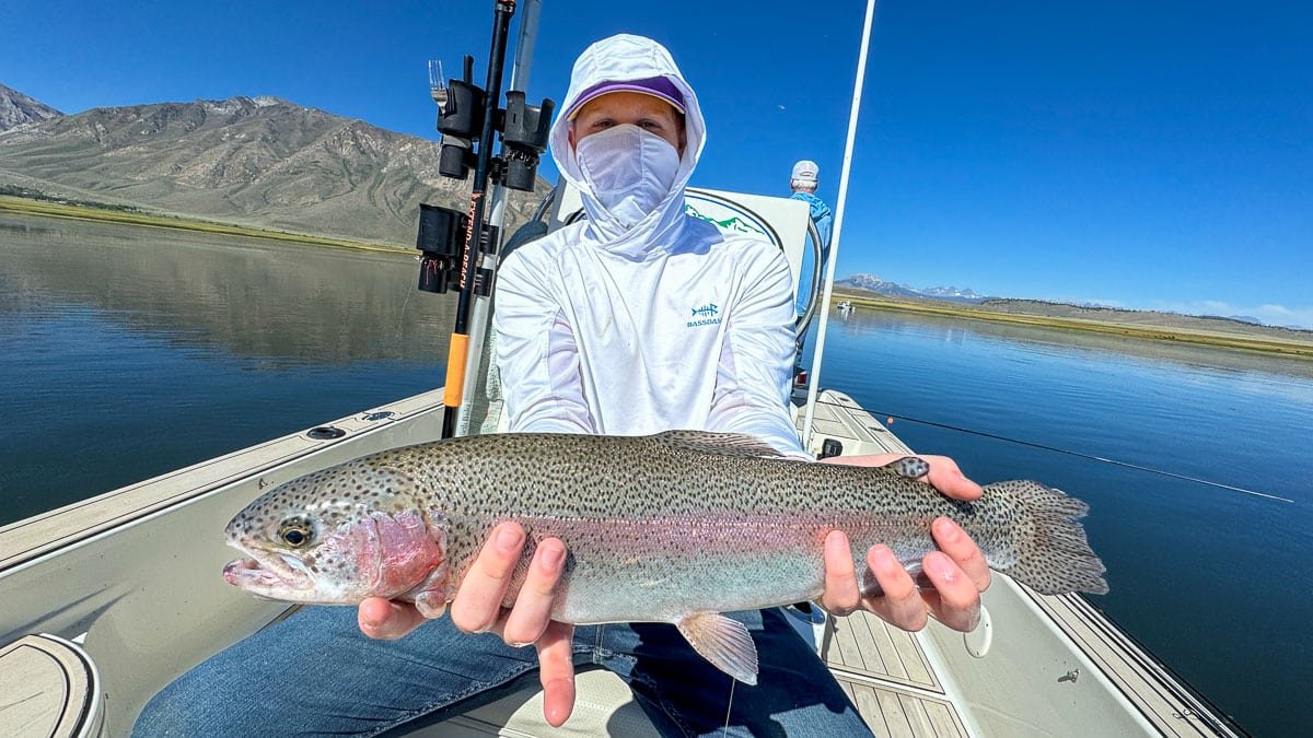 A fly fisherman holding a large rainbow trout on Crowley Lake near Mammoth Lakes, CA