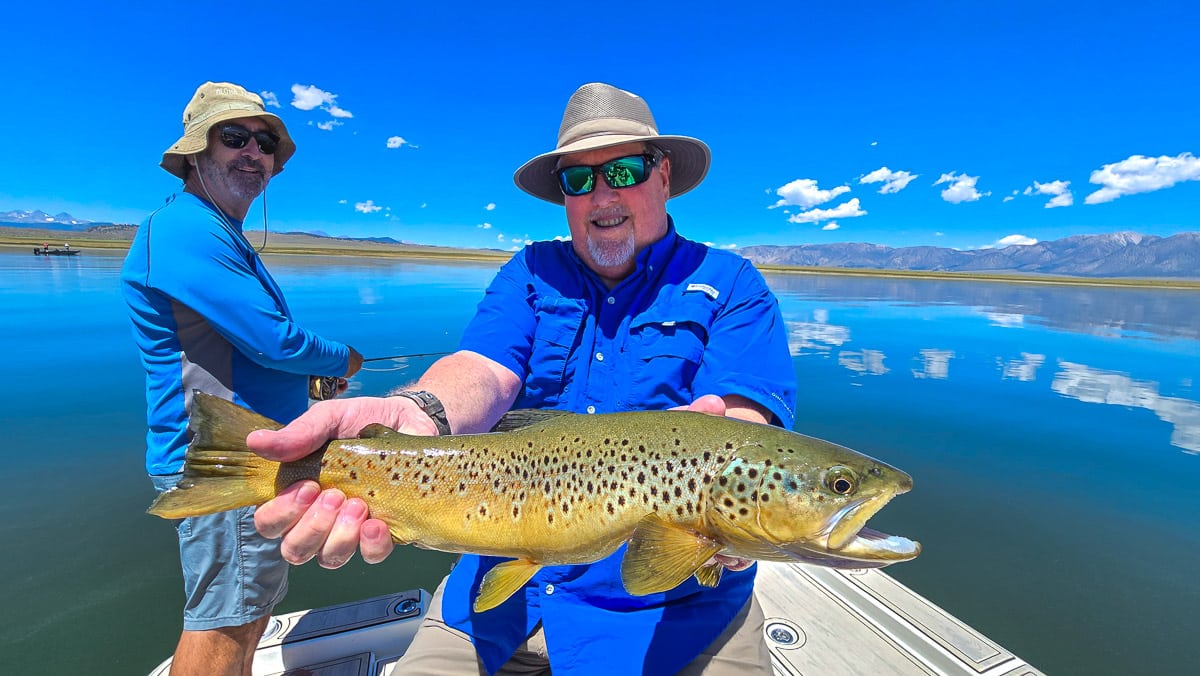 A fly fisherman holding a large rainbow trout on Crowley Lake near Mammoth Lakes, CA