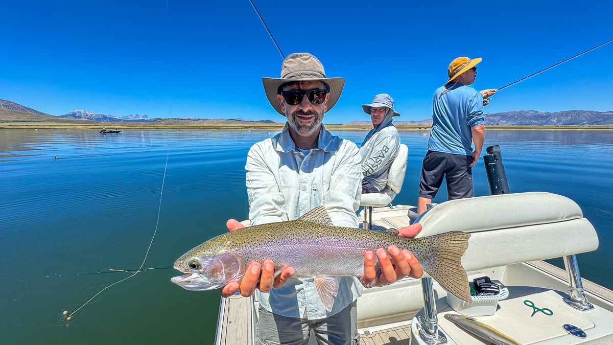 A fly fisherwoman holding a large rainbow trout on Crowley Lake near Mammoth Lakes, CA