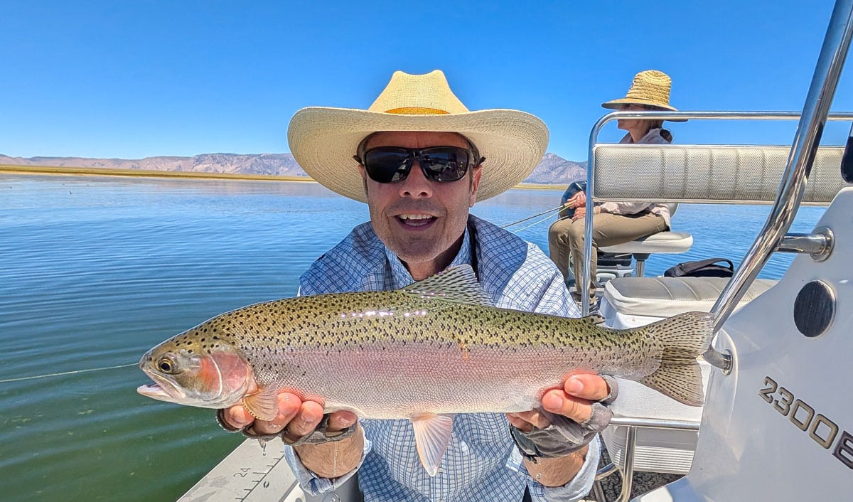 A fly fisherman holding a large brown trout on Crowley Lake near Mammoth Lakes, CA