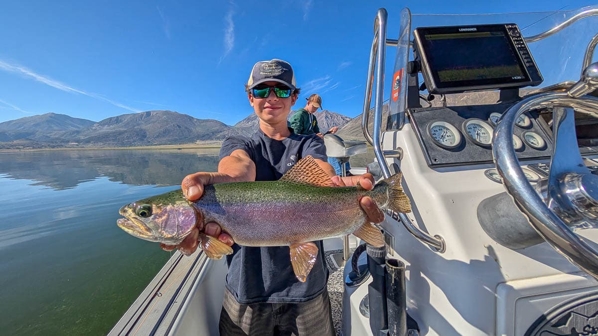A fly fisherman holding a large brown trout on Crowley Lake near Mammoth Lakes, CA