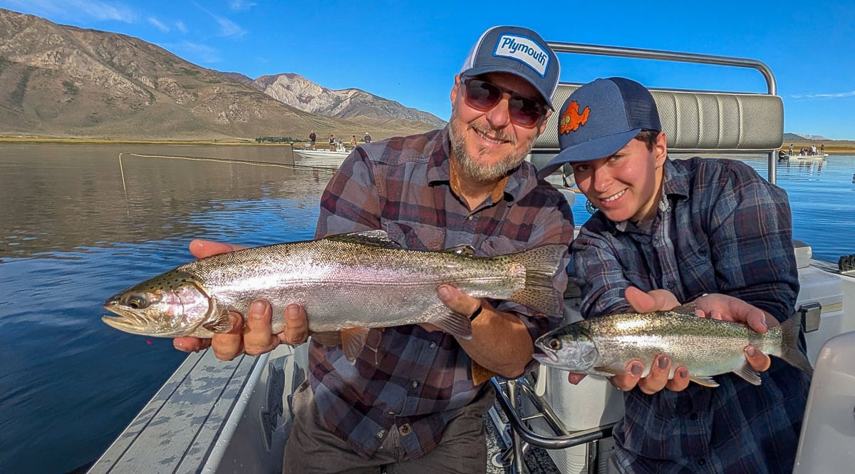 A smiling fly fisherman holding a large brown trout on the Crowley Lake near Mammoth Lakes, CA.