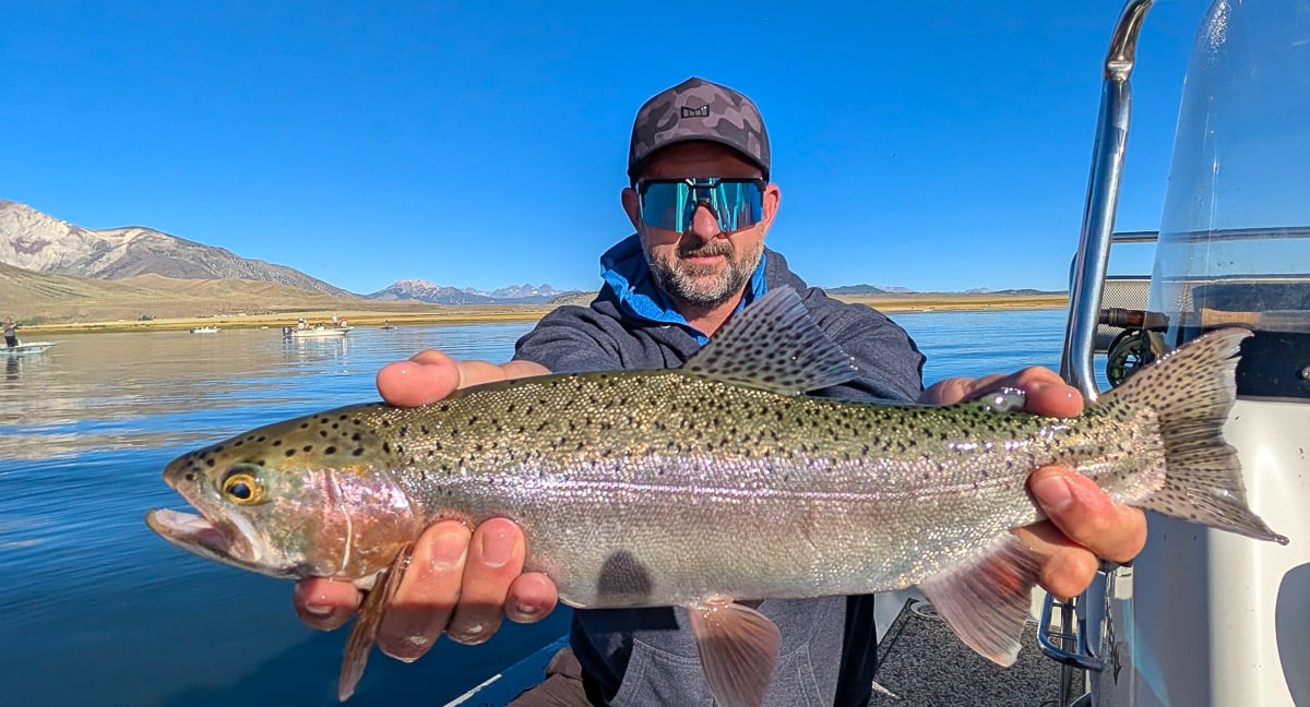 A fly fisherwoman holding a large rainbow trout on Crowley Lake near Mammoth Lakes, CA