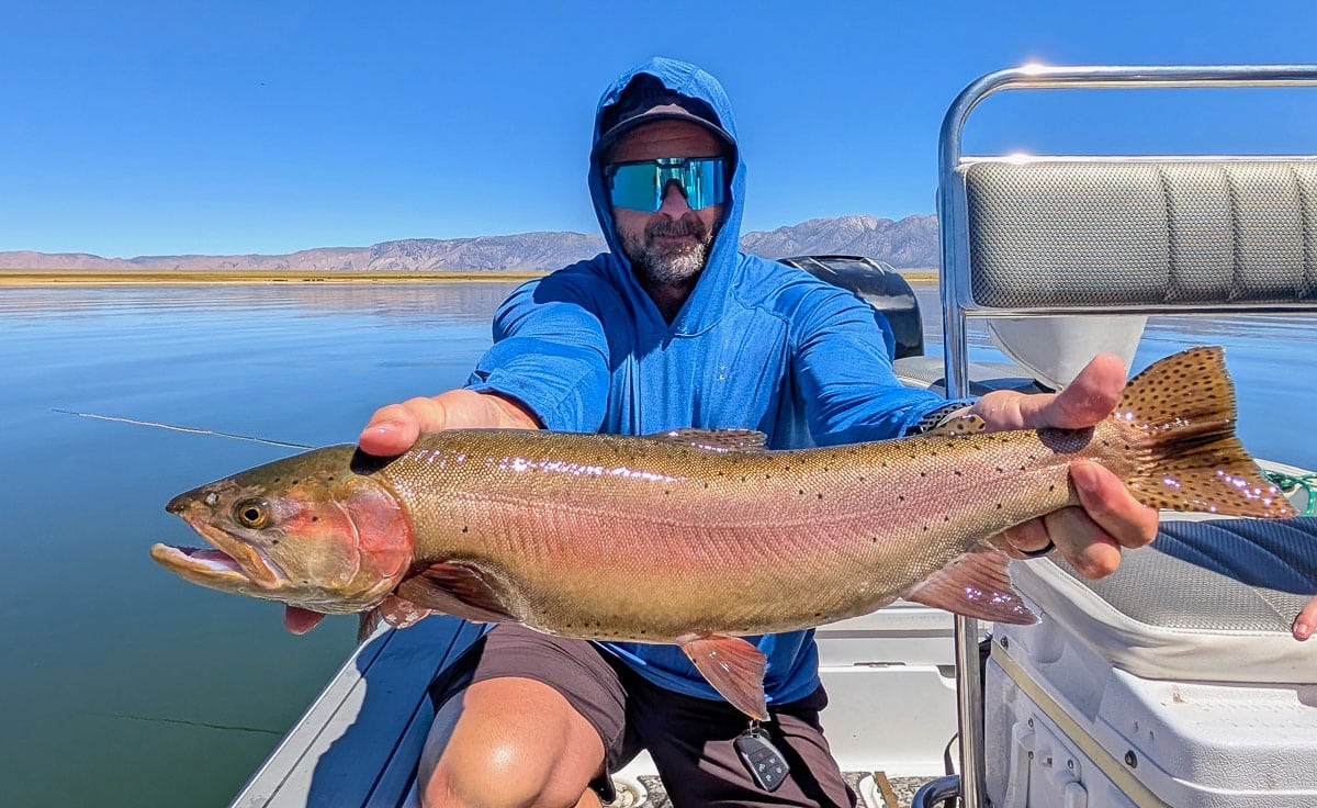 A fly fisherman holding a large brown trout on Crowley Lake near Mammoth Lakes, CA