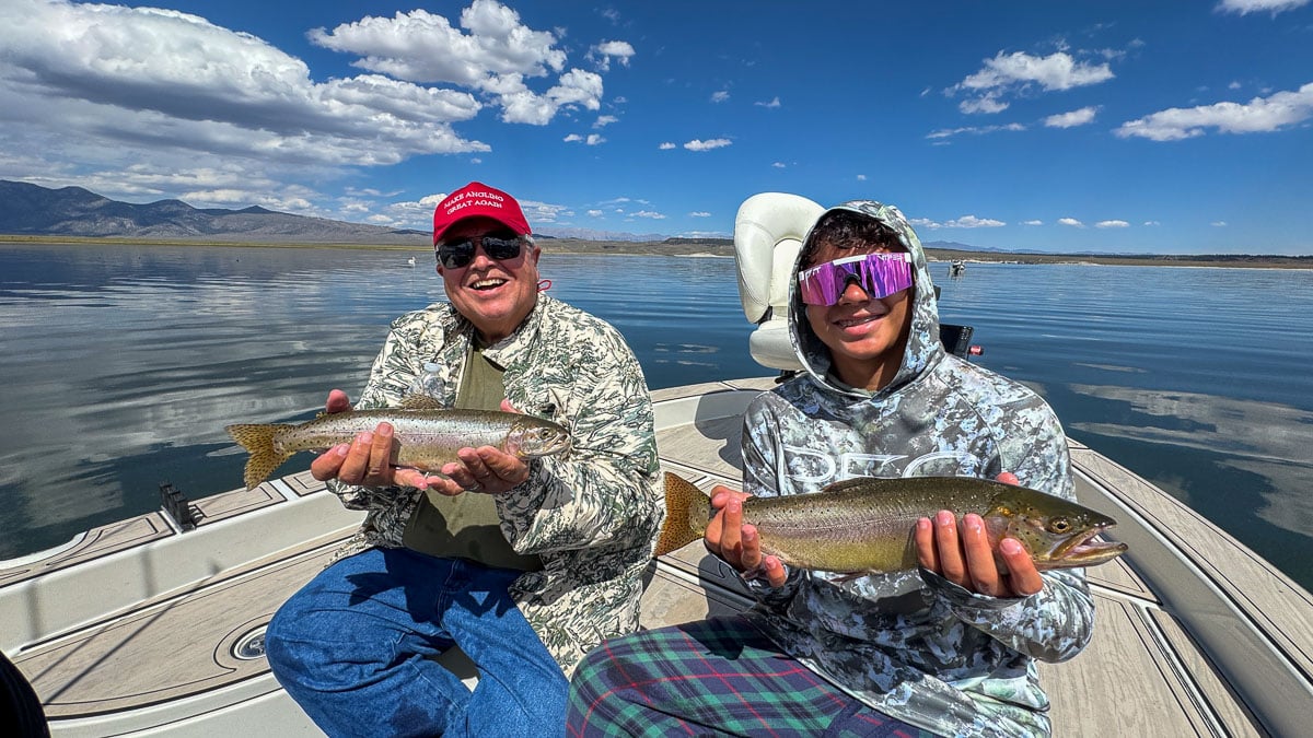 A fly fisherman holding a large brown trout on Crowley Lake near Mammoth Lakes, CA