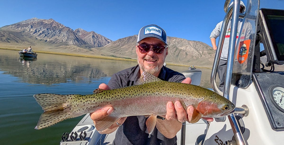 A female fly fisherman holding a large brown trout on Crowley Lake near Mammoth Lakes, CA
