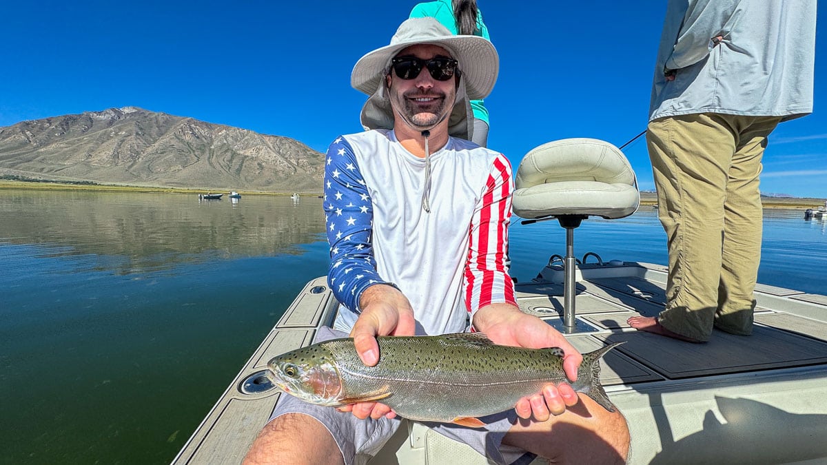 A fly fisherman holding a large brown trout on Crowley Lake near Mammoth Lakes, CA