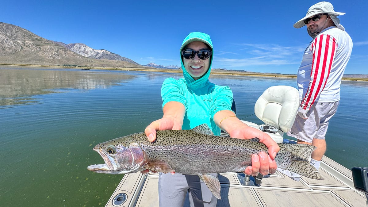 A fly fisherman holding a large rainbow trout on Crowley Lake near Mammoth Lakes, CA.