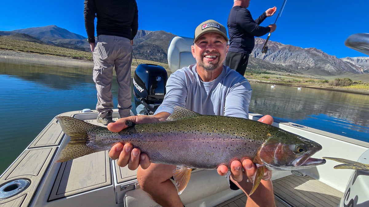 A fly fisherman holding a large rainbow trout on Crowley Lake near Mammoth Lakes, CA