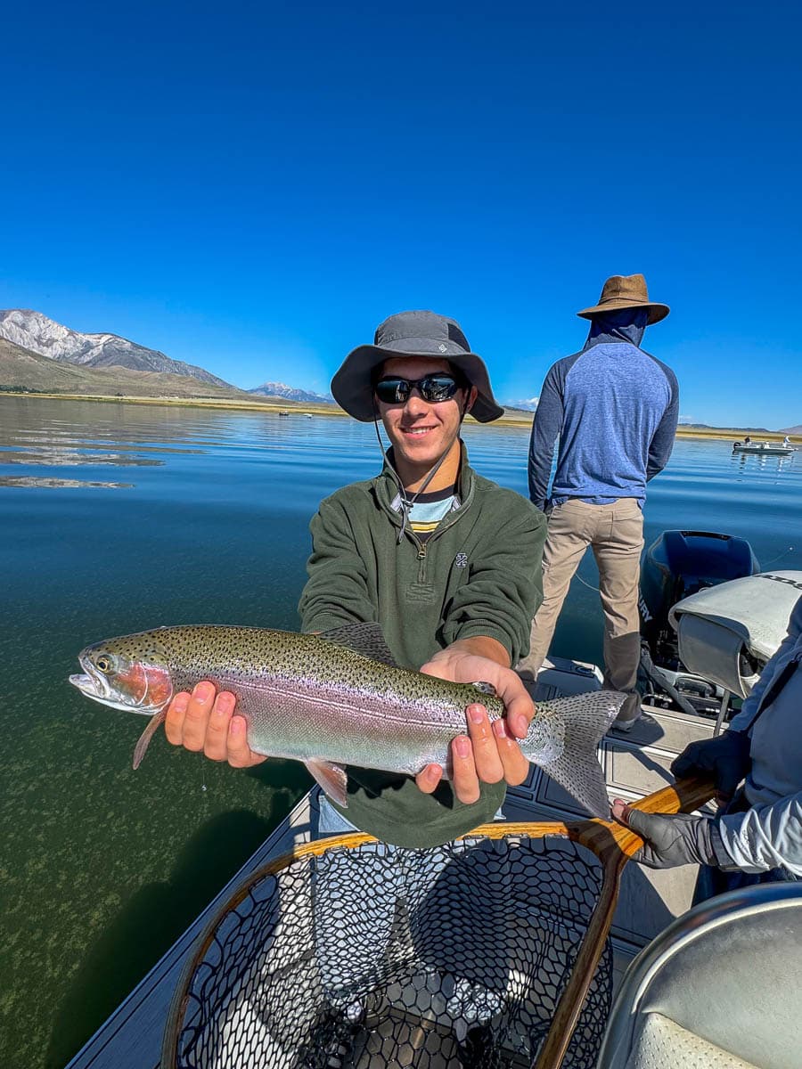 A fly fisherwoman holding a large rainbow trout on Crowley Lake near Mammoth Lakes, CA
