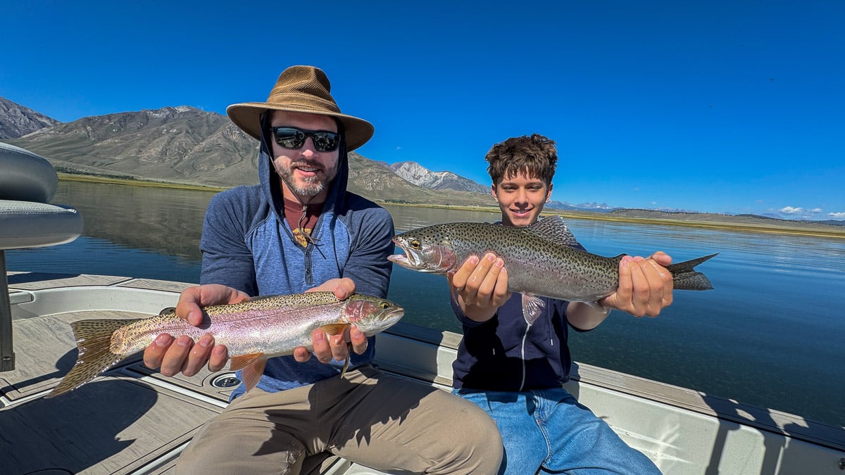 A smiling fly fisherman holding a large brown trout on the Crowley Lake near Mammoth Lakes, CA.