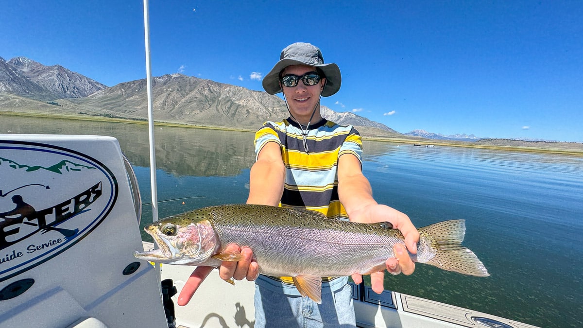 A fly fisherman holding a large brown trout on Crowley Lake near Mammoth Lakes, CA