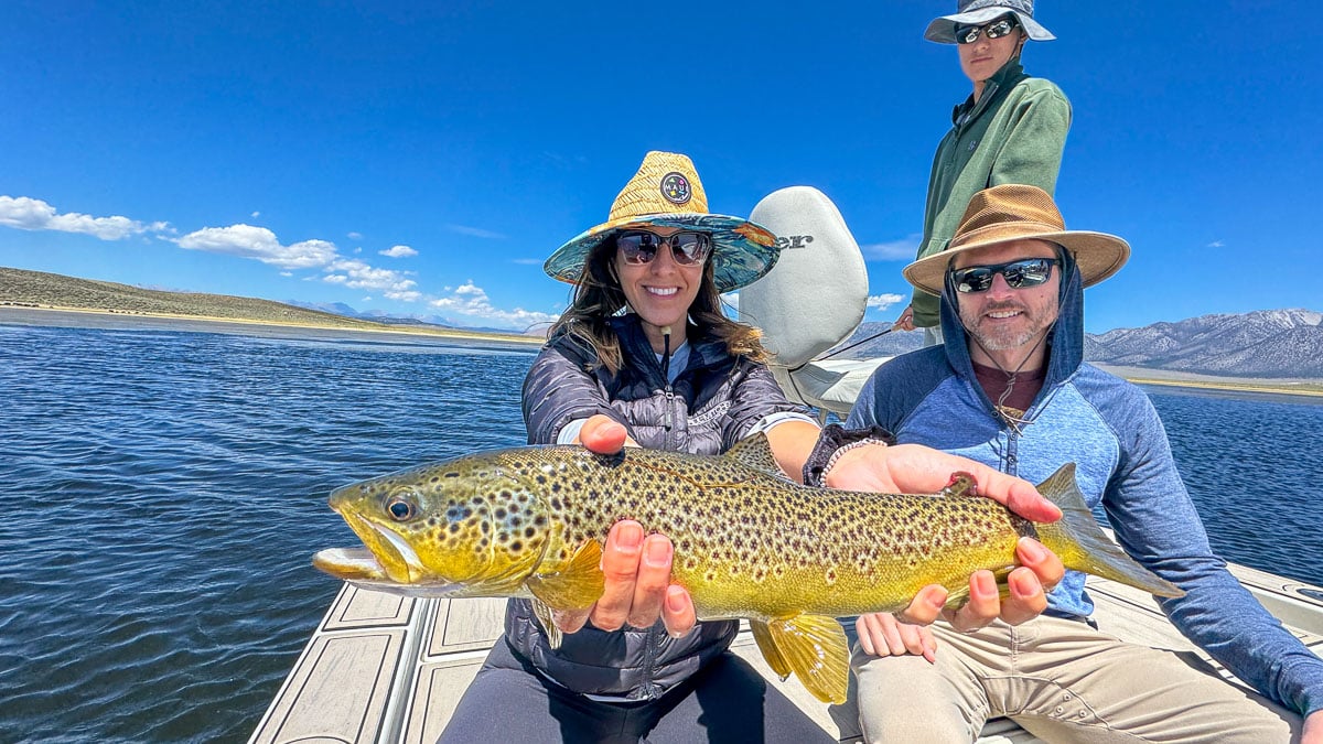 A fly fisherwoman holding a large rainbow trout on Crowley Lake near Mammoth Lakes, CA