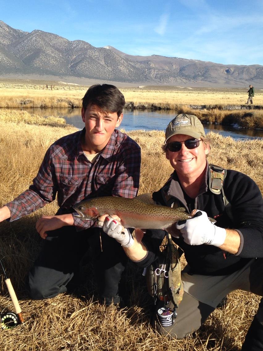 A fly fisherman holding a large rainbow trout on Crowley Lake near Mammoth Lakes, CA