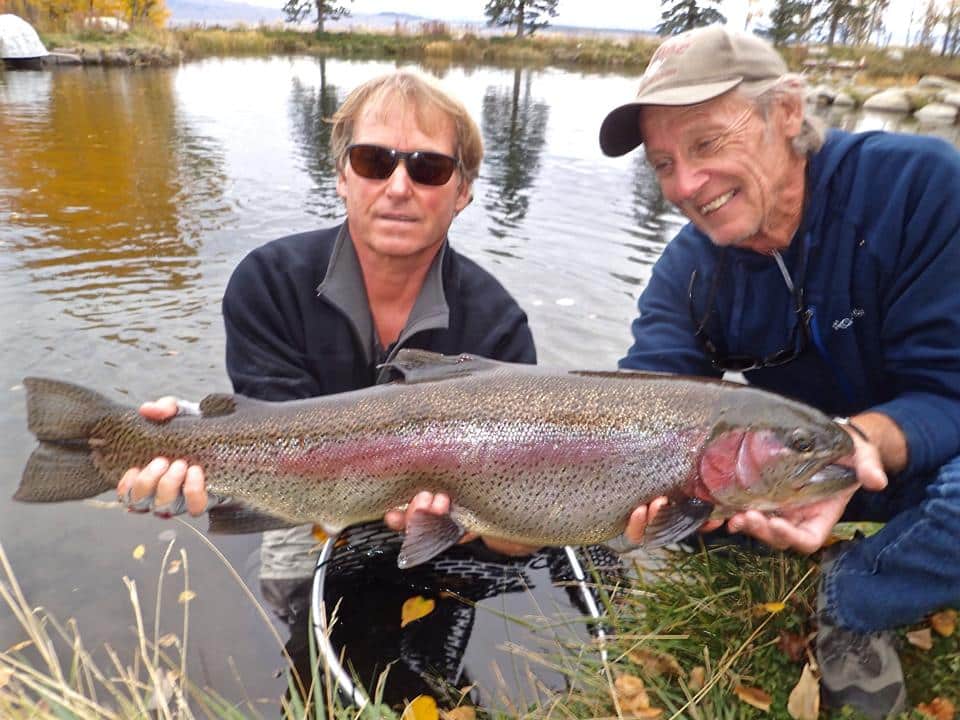 A fly fisherman holding a large brown trout on Crowley Lake near Mammoth Lakes, CA