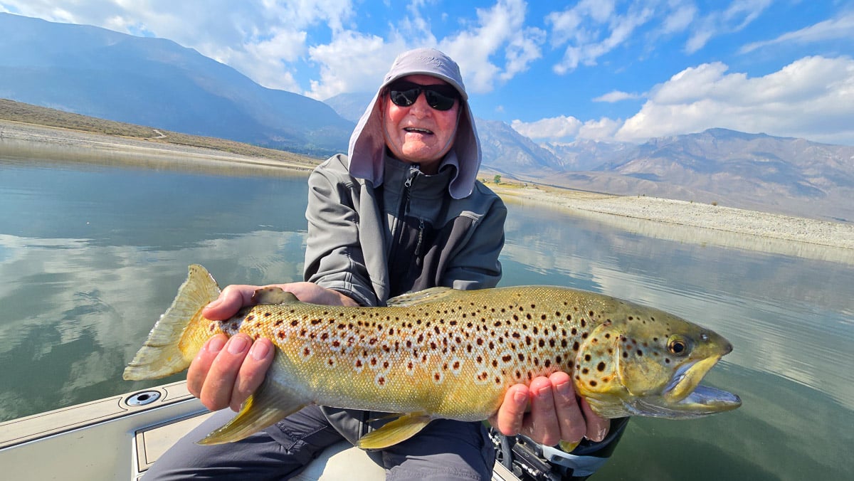 A fly fisherwoman holding a large rainbow trout on Crowley Lake near Mammoth Lakes, CA