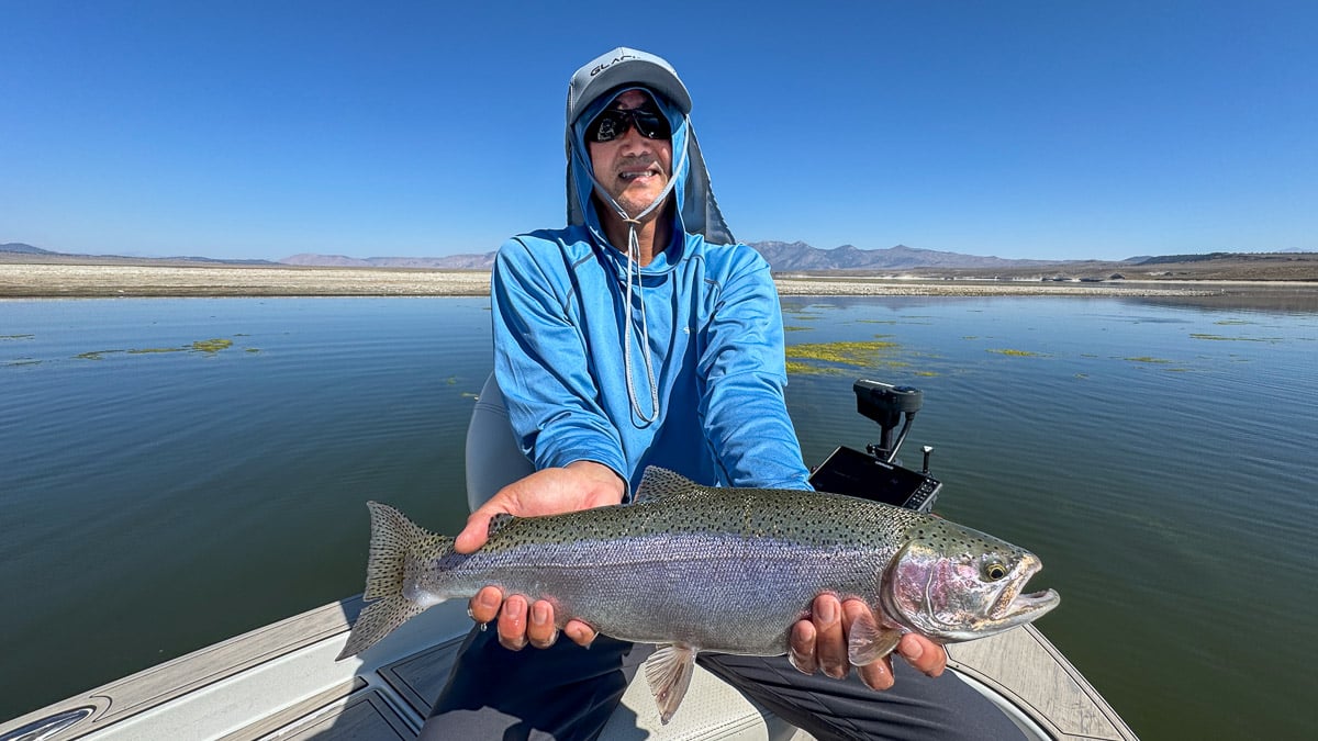 A fly fisherman holding a large rainbow trout on Crowley Lake near Mammoth Lakes, CA