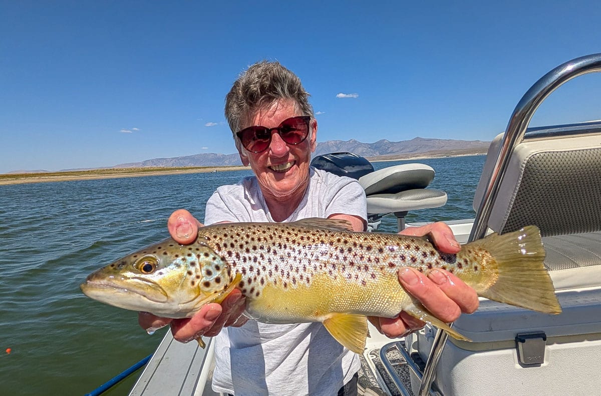A fly fisherman holding a large rainbow trout on Crowley Lake near Mammoth Lakes, CA