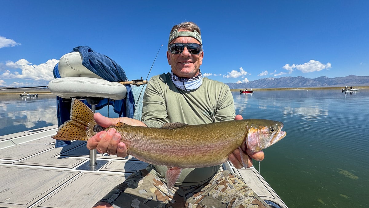 A fly fisherman holding a large cutthroat trout on Crowley Lake near Mammoth Lakes, CA