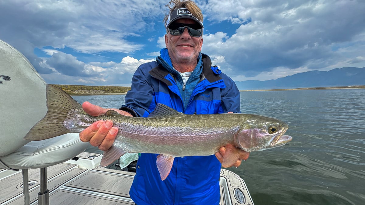 A fly fisherman holding a large rainbow trout on Crowley Lake near Mammoth Lakes, CA
