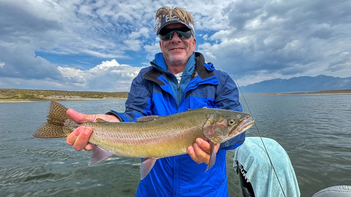 A female fly fisherman holding a large brown trout on Crowley Lake near Mammoth Lakes, CA