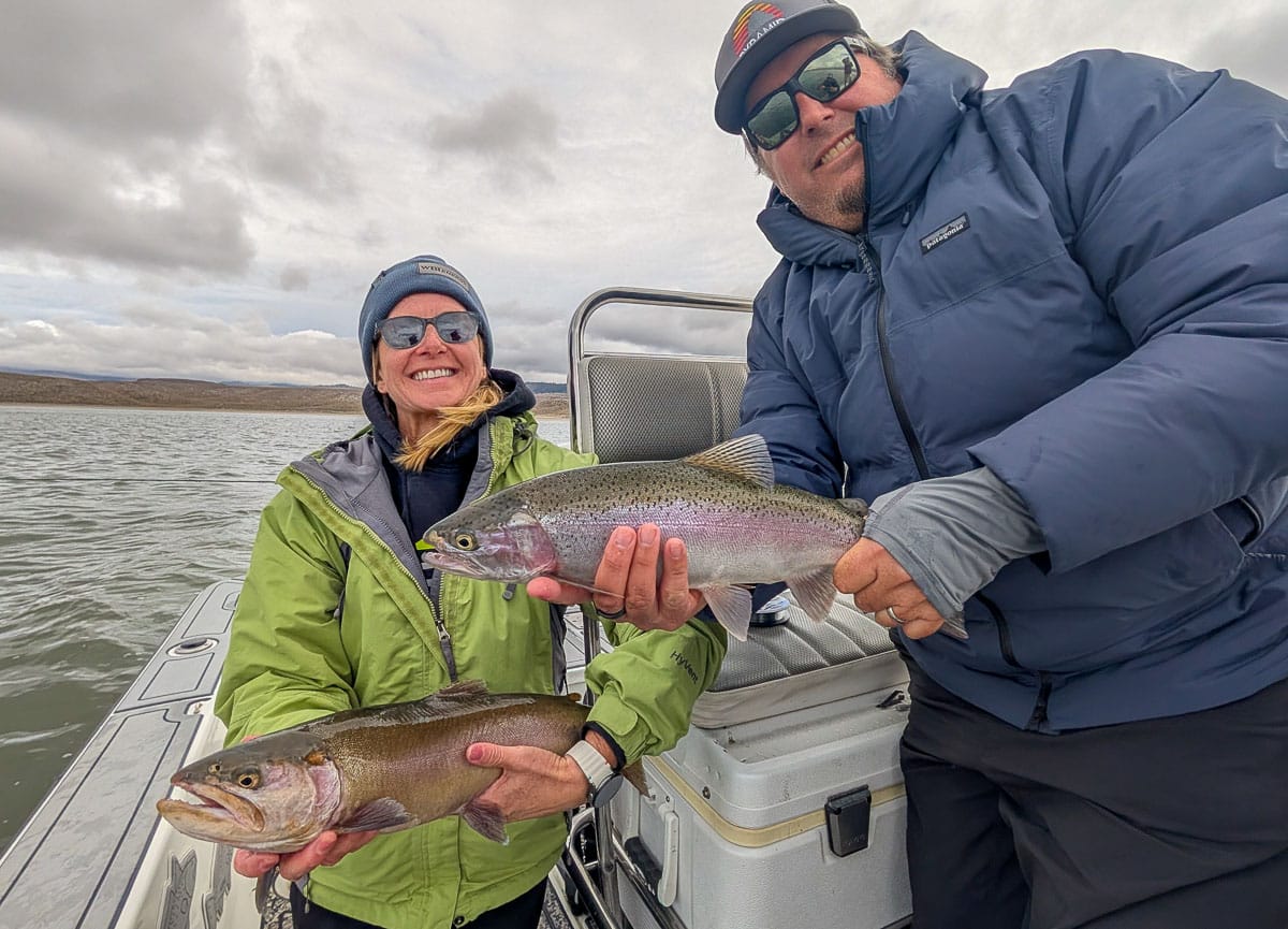 A smiling fly fisherman holding a large brown trout on the Crowley Lake near Mammoth Lakes, CA.