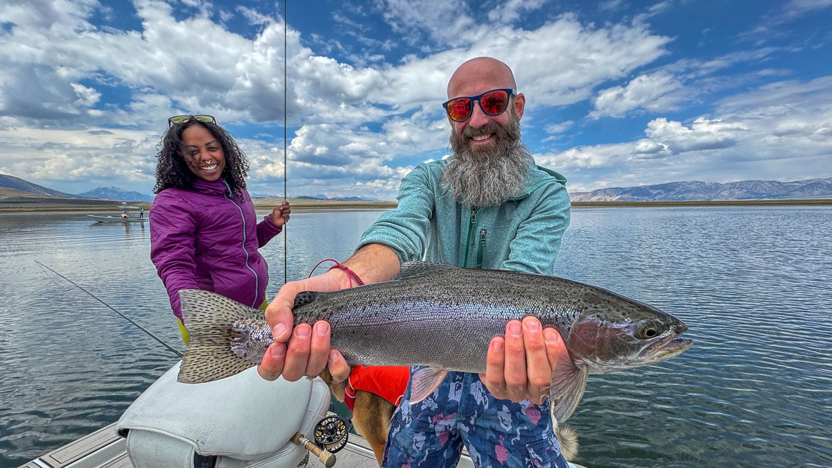 A fly fisherman holding a large rainbow trout on Crowley Lake.