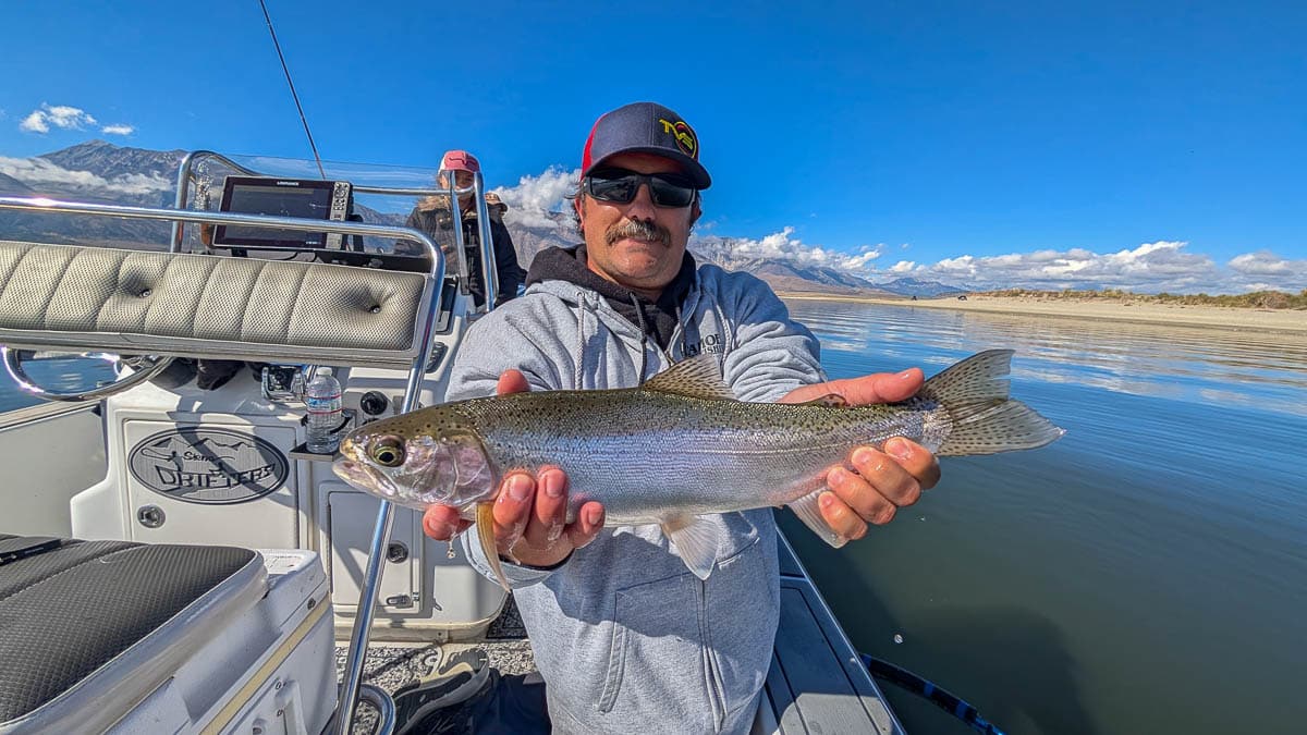 A fly fisherman holding a large brown trout on Crowley Lake near Mammoth Lakes, CA