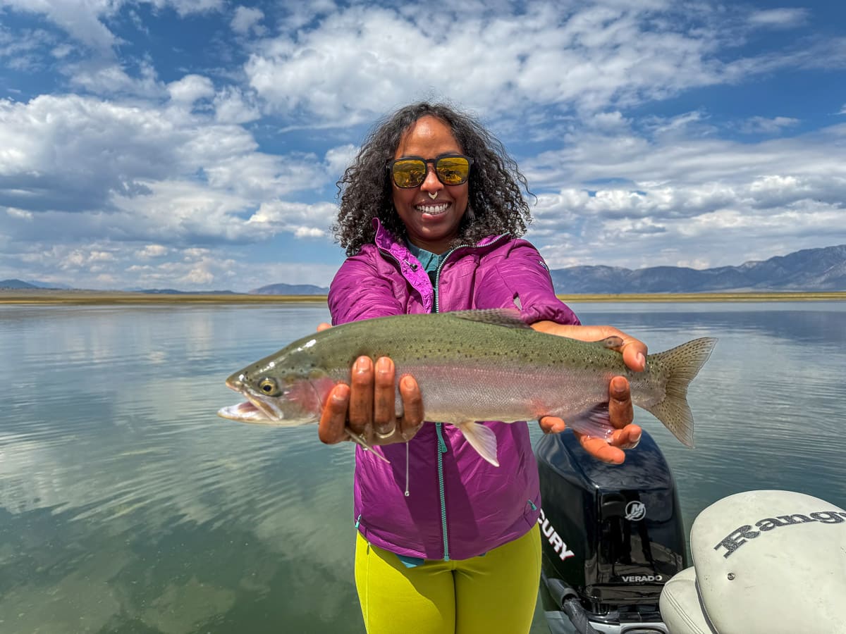 A fly fisherman holding a large brown trout on Crowley Lake near Mammoth Lakes, CA