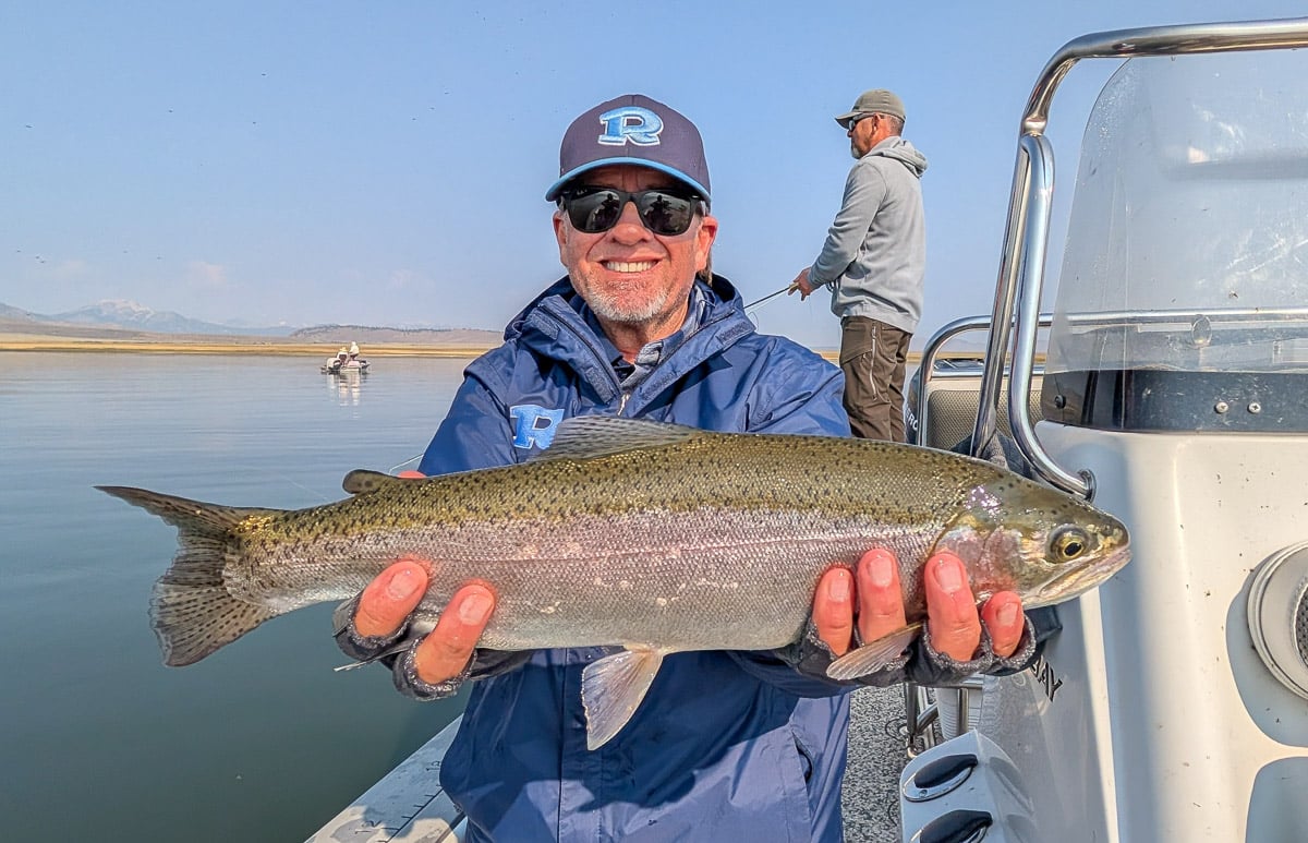 A fly fisherman holding a large rainbow trout on East Walker River near Bridgeport, CA