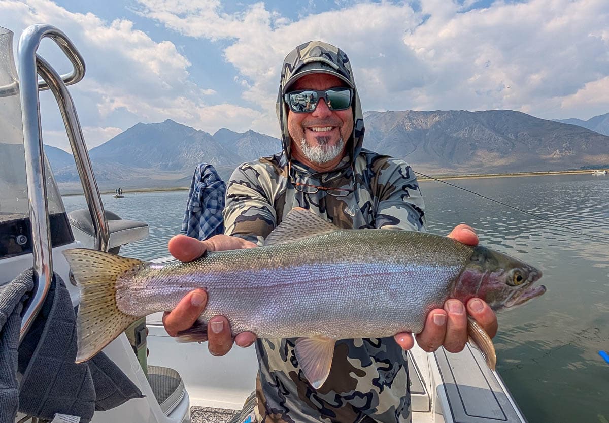 A fly fisherman holding a large rainbow trout on Crowley Lake near Mammoth Lakes, CA.