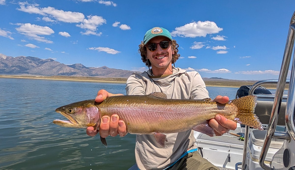 A fly fisherman holding a large brown trout on Crowley Lake near Mammoth Lakes, CA