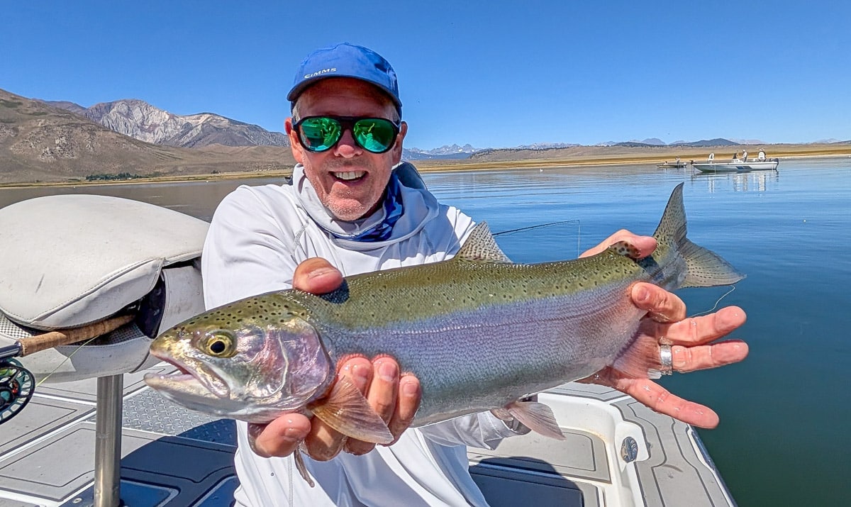 A fly fisherman holding a large brown trout on Crowley Lake near Mammoth Lakes, CA