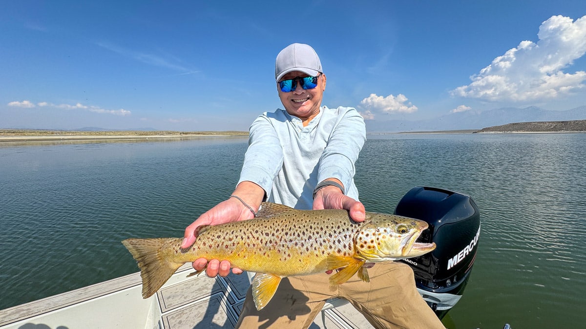A fly fisherman holding a large brown trout on Crowley Lake near Mammoth Lakes, CA
