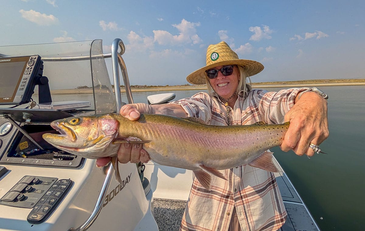 A smiling fly fisherman holding a large brown trout on the Crowley Lake near Mammoth Lakes, CA.