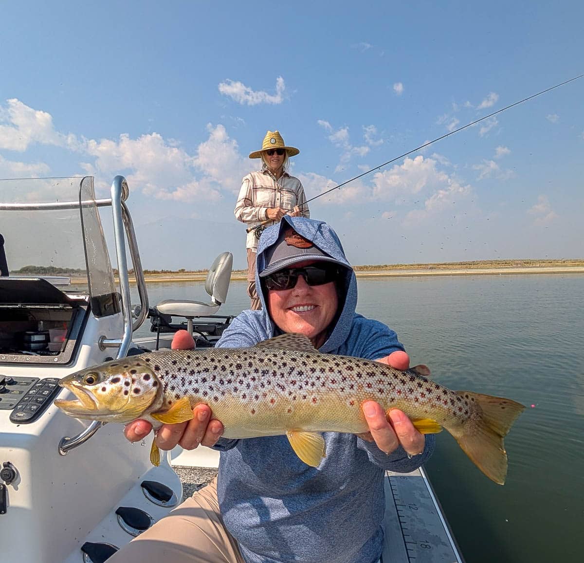 A fly fisherman holding a large brown trout on Crowley Lake near Mammoth Lakes, CA