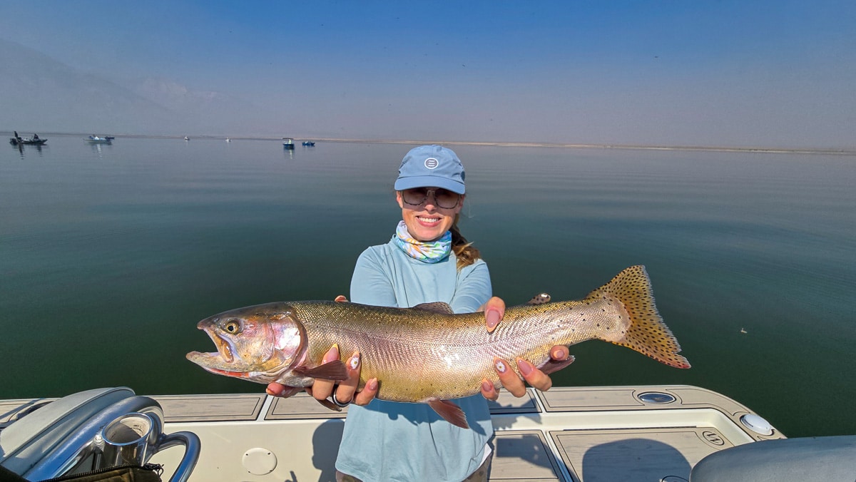 A female fly fisherman holding a large brown trout on Crowley Lake near Mammoth Lakes, CA