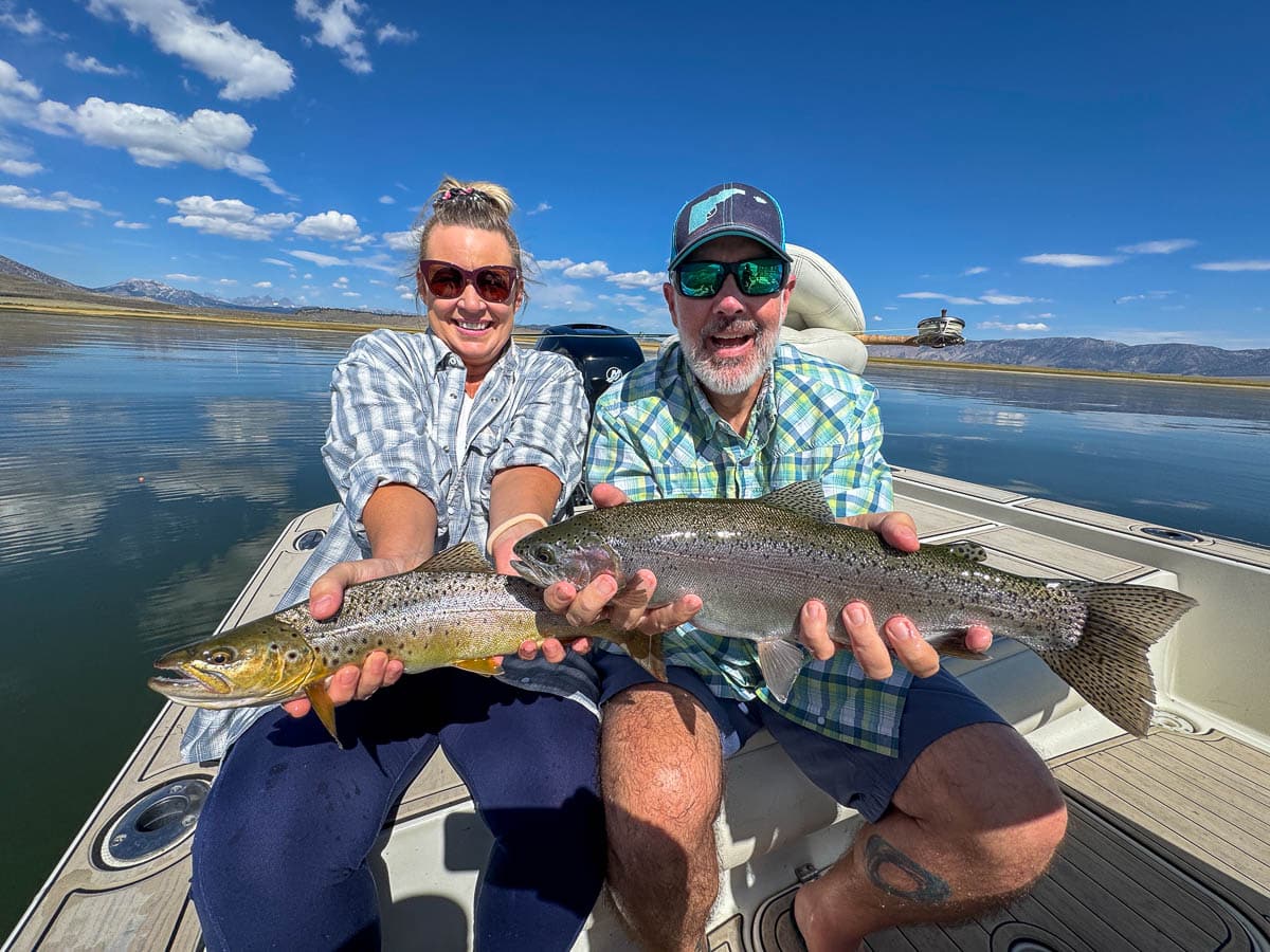 A fly fisherman holding a large brown trout on Crowley Lake near Mammoth Lakes, CA