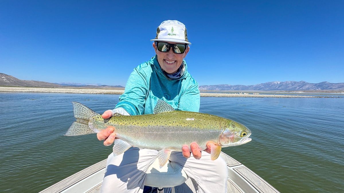 A fly fisherman holding a large brown trout on Crowley Lake near Mammoth Lakes, CA