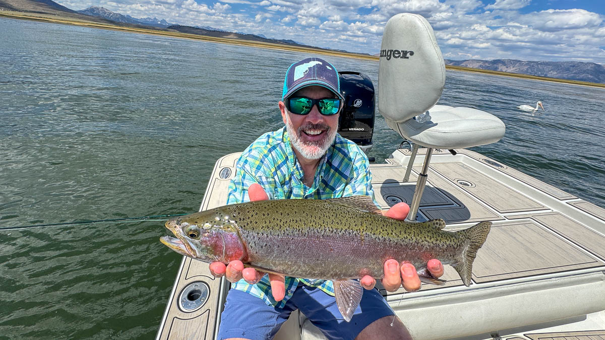 A fly fisherwoman holding a large rainbow trout on Crowley Lake near Mammoth Lakes, CA