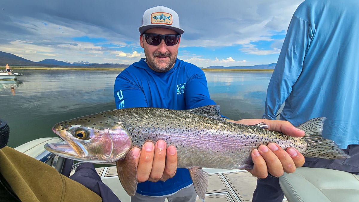 A fly fisherman holding a large brown trout on Crowley Lake near Mammoth Lakes, CA