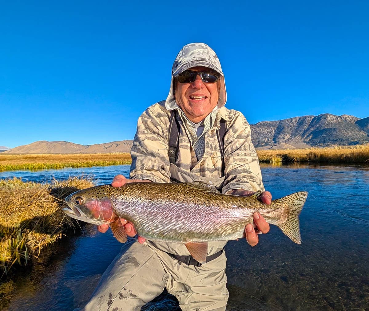 A fly fisheman holding a large rainbow trout on the Upper Owens River near Mammoth Lakes, CA