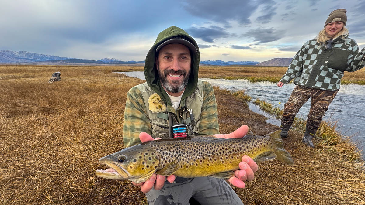 A fly fisheman holding a large brown trout on the Upper Owens River near Mammoth Lakes, CA