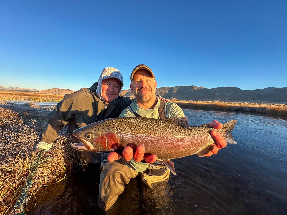 A fly fisheman holding a large rainbow trout on the Upper Owens River near Mammoth Lakes, CA